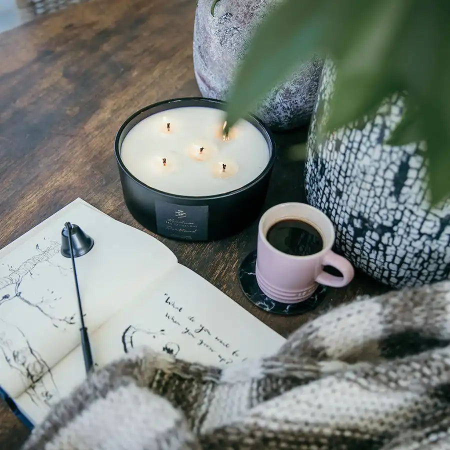 A large, black, multi-wick candle with a white wax.