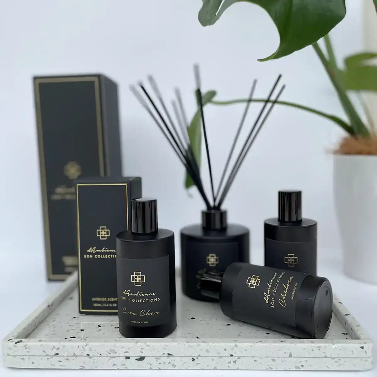 A collection of black home fragrance products, including diffusers and sprays, with gold accents.