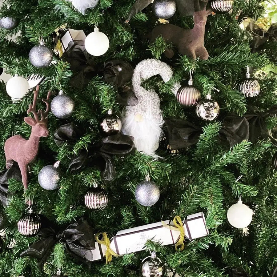 Festive cracker with Christmas tree, black bows, silver ornaments, gnome, deer, and cracker