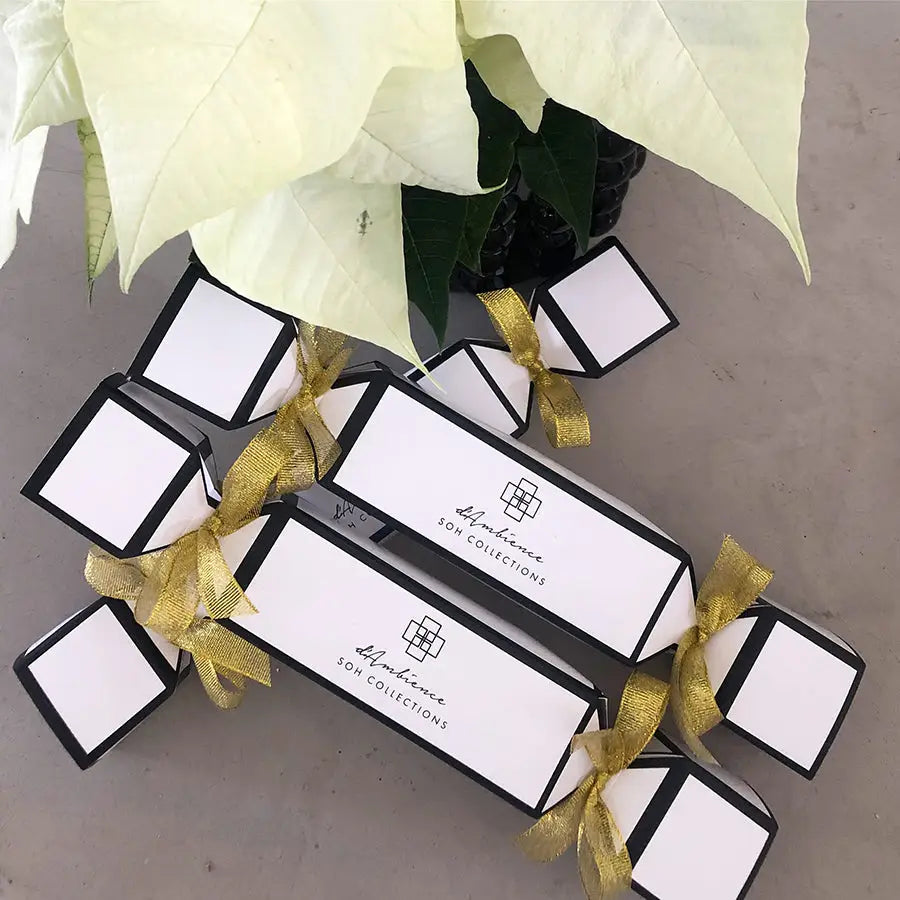 Black and white rectangular gift boxes with gold ribbons for Festive Cracker scent diffuser