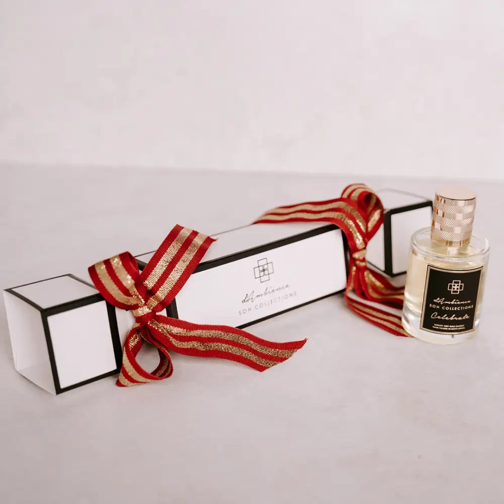 Festive Christmas cracker with a white gift box, red gold ribbon, and glass perfume