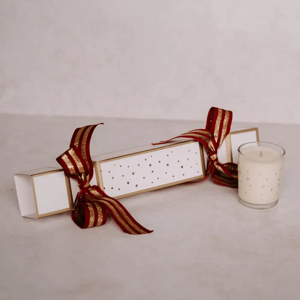 Festive Christmas cracker with gold stars and matching candle in glass votive