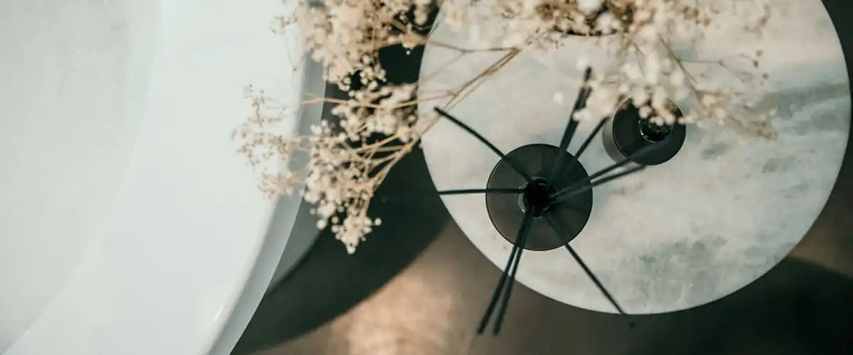 White dried flowers in a dark, multi-stemmed vase.